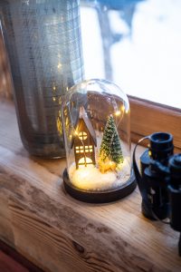 Dekoration Herbst Winter Collection, Eine Schneekugel, eine Vase und ein Fernglas stehen auf einer Fensterbank